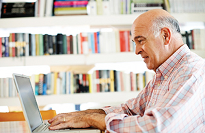 older man typing on a laptop